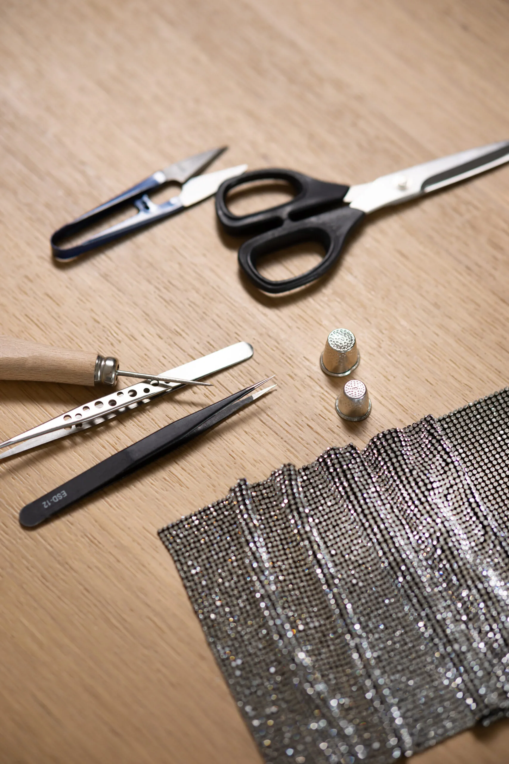 Le mani di un artigiano al lavoro sulla maglia di cristalli